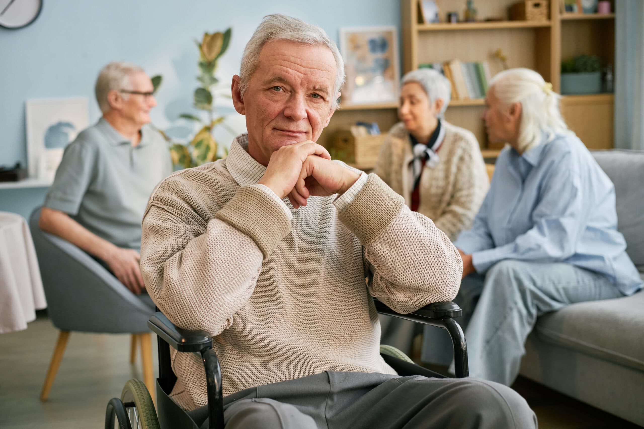 An older man seated in the lounge of an aged care home
