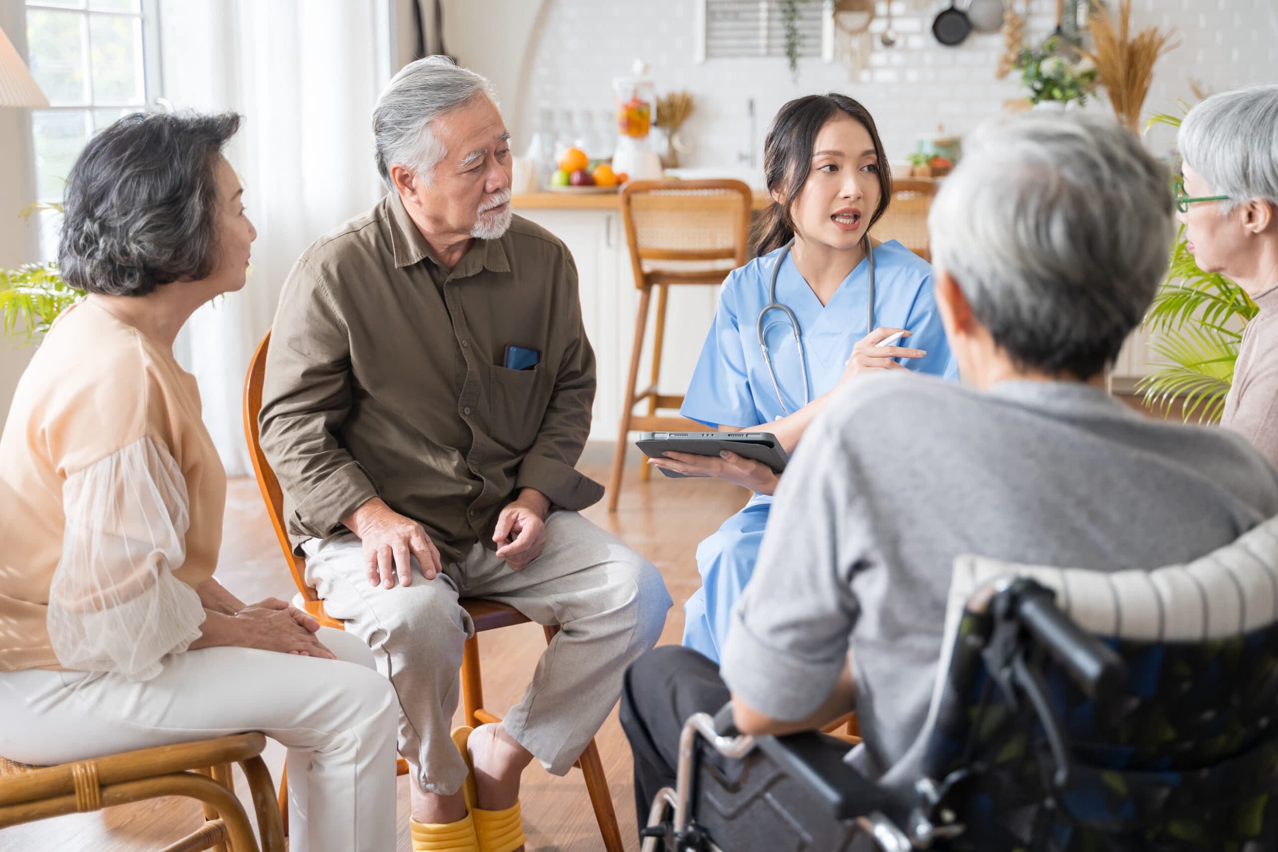 A nurse talking with older residents in a group