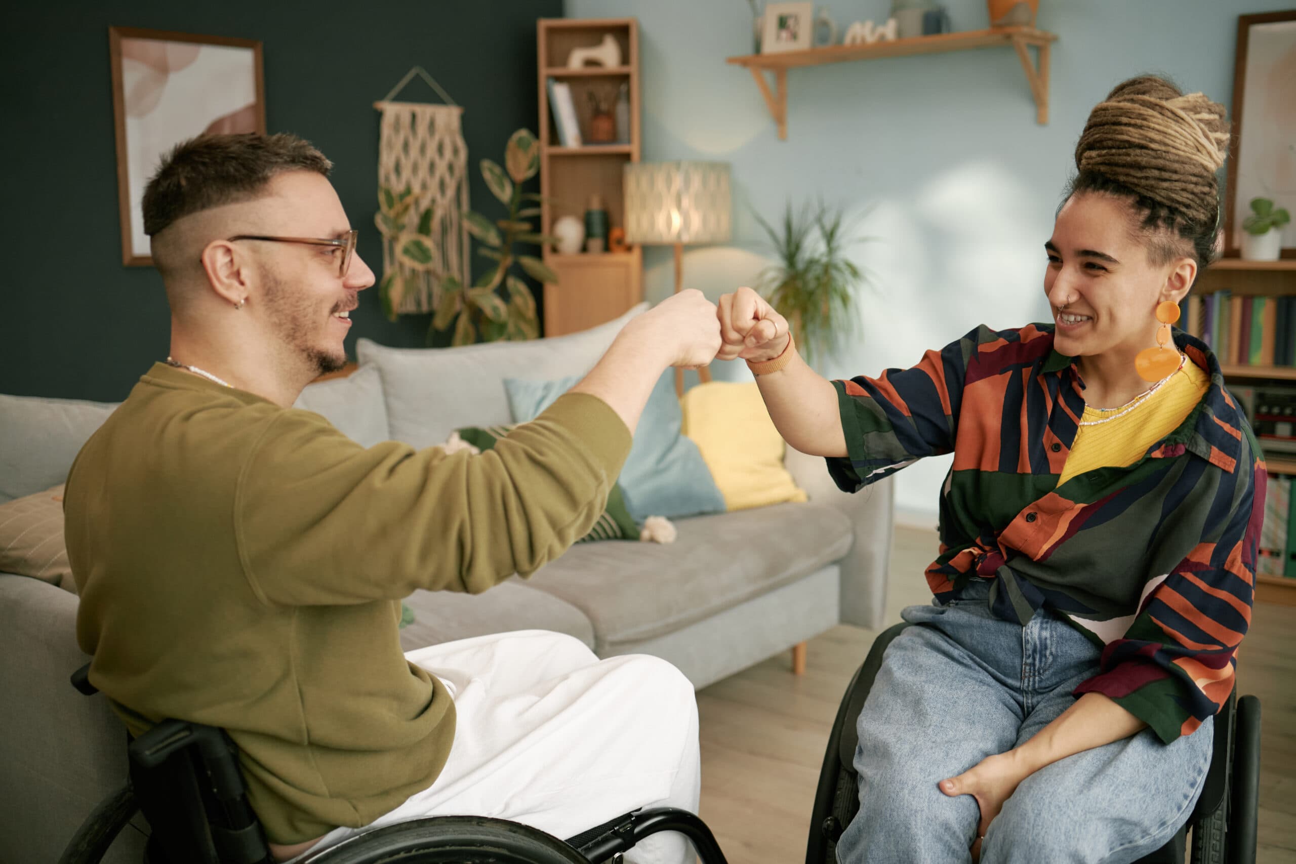 Two wheelchair users sharing a fist bump at home