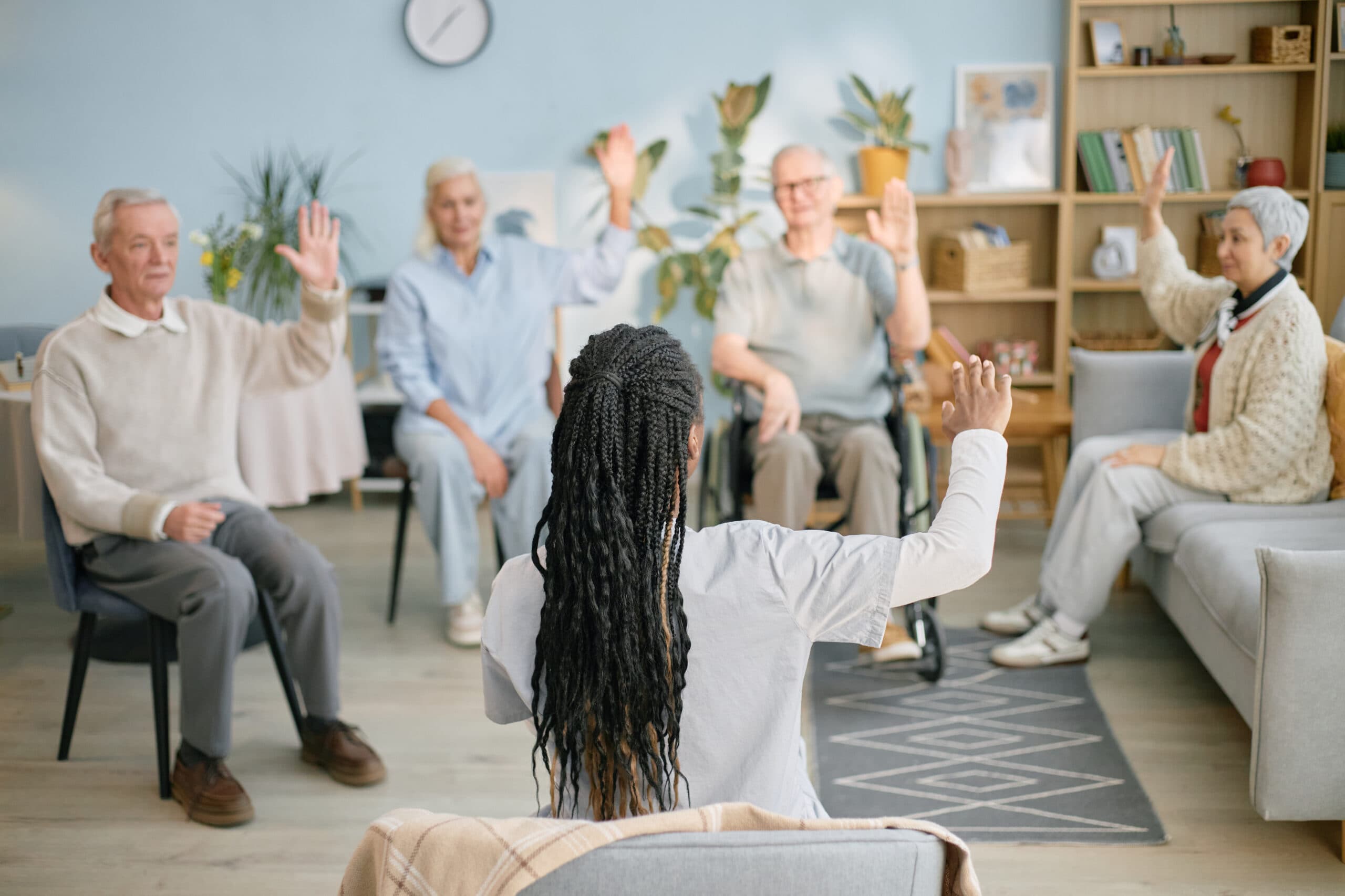 A care worker leading a group exercise session for older residents