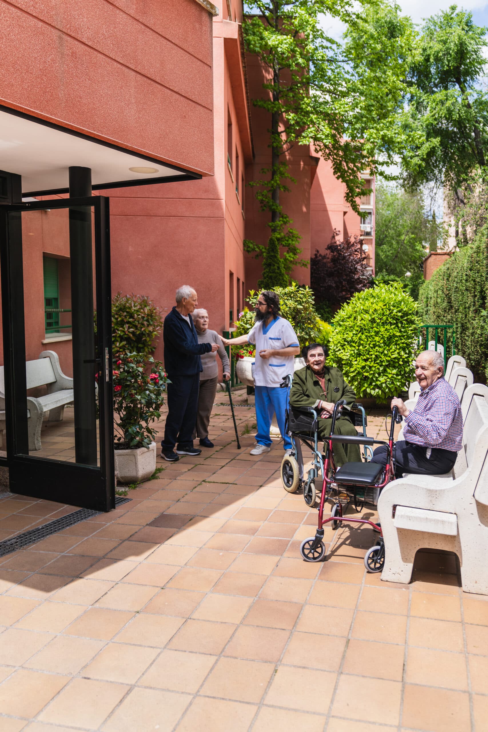Residents and a staff member in the courtyard of an aged care home